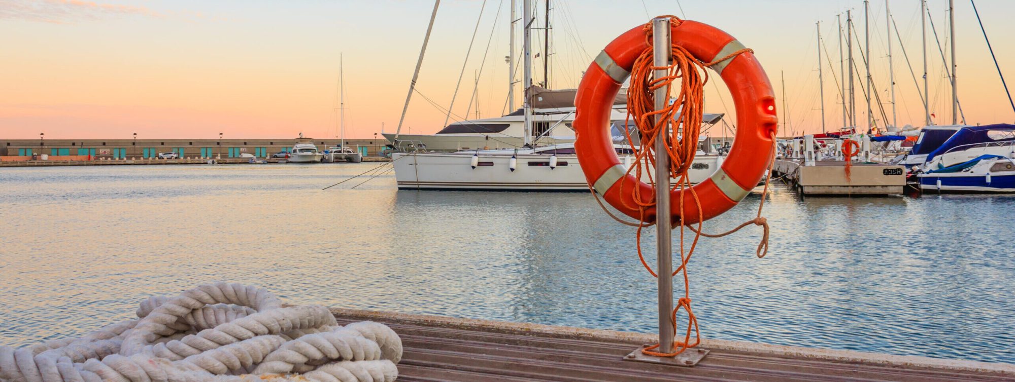 the quay of a marina at the sunset /a mooring rope with a lifebelt on the quay of a marina at the sunset
